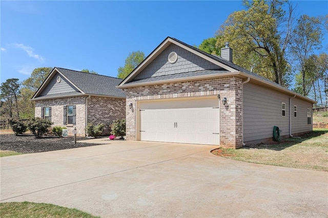view of front of home featuring an attached garage, a chimney, driveway, and brick siding
