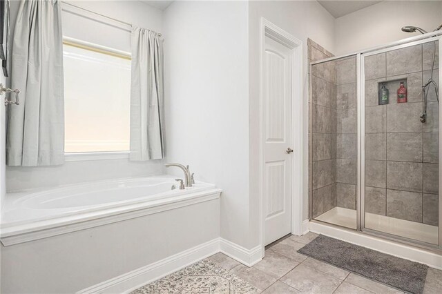 bathroom featuring a shower stall, tile patterned floors, a bath, and baseboards