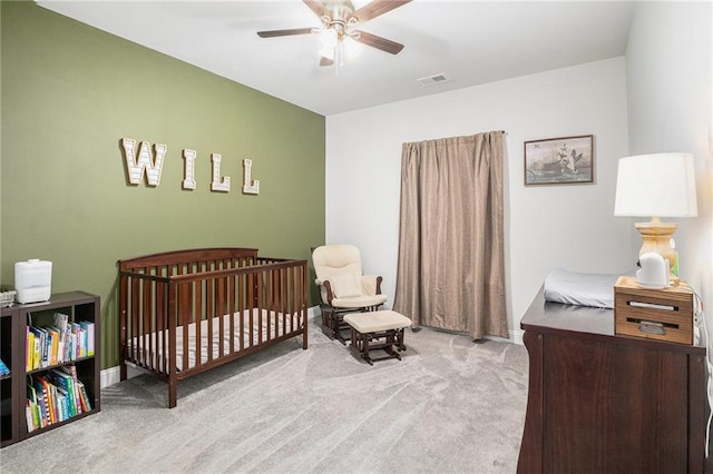 carpeted bedroom with baseboards, a ceiling fan, visible vents, and a crib