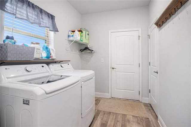 laundry room with light wood-type flooring, separate washer and dryer, laundry area, and baseboards