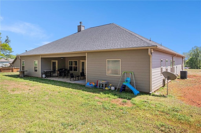 back of house featuring a patio, roof with shingles, a chimney, central AC unit, and a yard