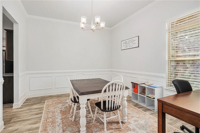 dining space with a wainscoted wall, an inviting chandelier, crown molding, and wood finished floors