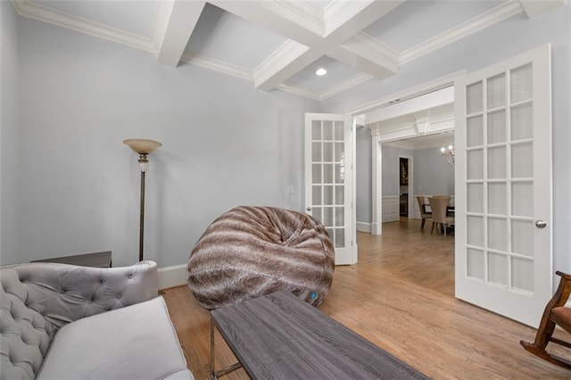living area featuring coffered ceiling, beamed ceiling, ornamental molding, wood finished floors, and french doors