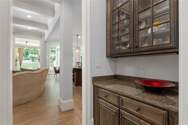 bar area featuring ornamental molding and light wood finished floors