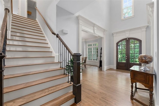 entryway with a high ceiling, stairway, wood finished floors, french doors, and baseboards