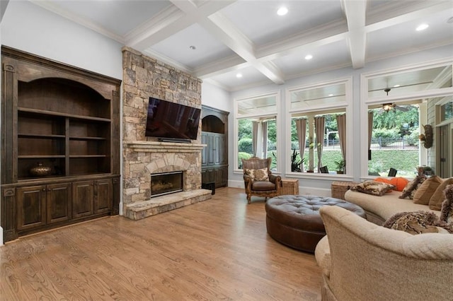 living area featuring a stone fireplace, healthy amount of natural light, light wood-type flooring, coffered ceiling, and beam ceiling