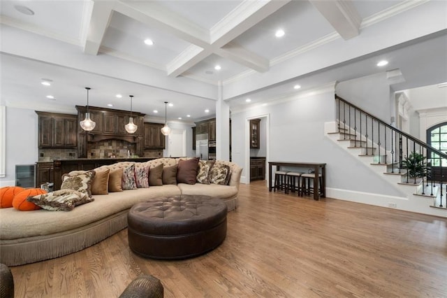living room with coffered ceiling, beam ceiling, light wood finished floors, stairs, and ornamental molding