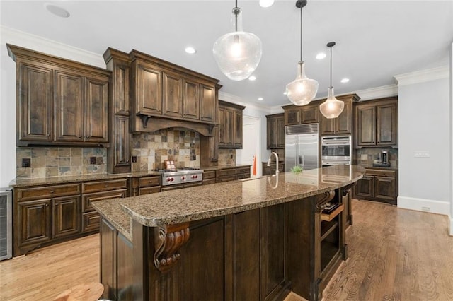 kitchen featuring appliances with stainless steel finishes, tasteful backsplash, ornamental molding, dark brown cabinetry, and dark stone countertops