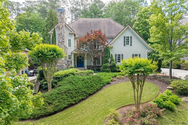 view of front facade featuring stone siding, a chimney, and a front yard