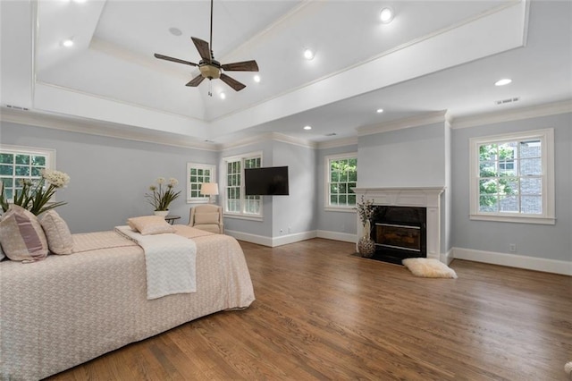 bedroom featuring wood finished floors, crown molding, baseboards, a high end fireplace, and recessed lighting