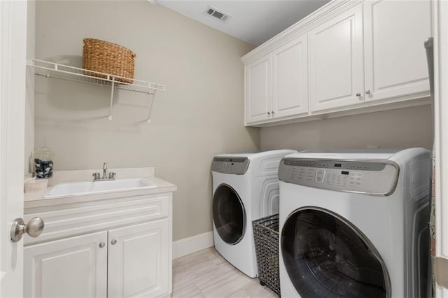 washroom with cabinet space, washer and clothes dryer, and baseboards