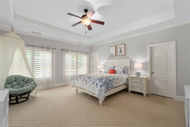 bedroom featuring a tray ceiling, carpet, crown molding, and a ceiling fan