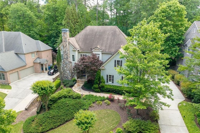 view of front facade featuring a chimney, driveway, an attached garage, and a tiled roof