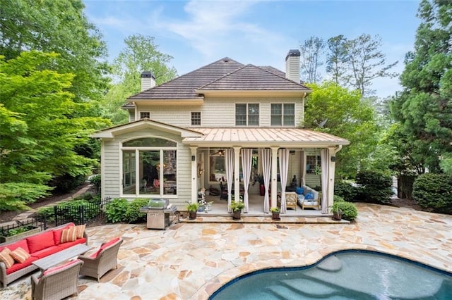 rear view of house featuring a chimney, an outdoor hangout area, a standing seam roof, and a patio area
