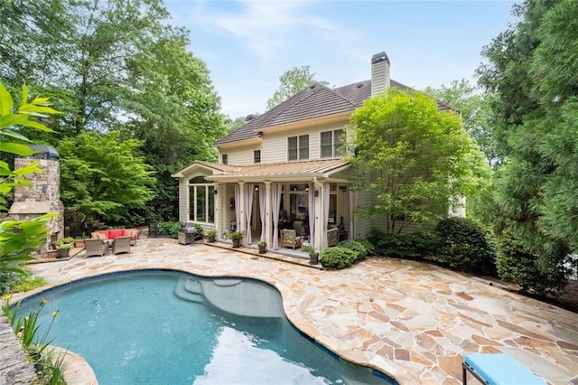 back of house with an outdoor hangout area, a patio, a chimney, and an outdoor pool