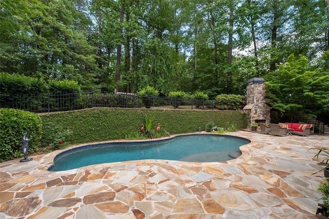 view of pool with a patio area, fence, and an outdoor living space with a fireplace
