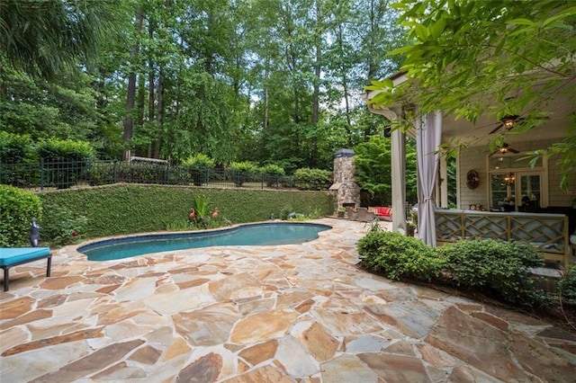 view of pool with a fenced backyard, a patio, a ceiling fan, and view of scattered trees