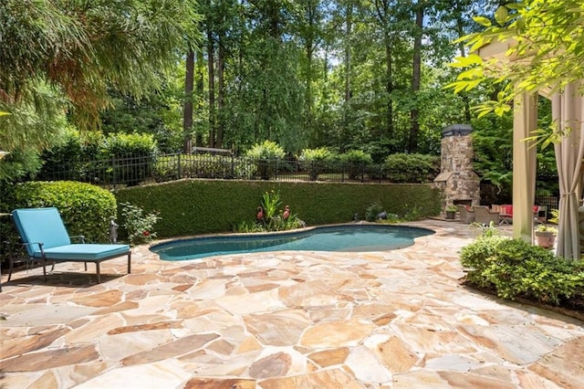 view of swimming pool featuring an outdoor stone fireplace, a patio area, and fence