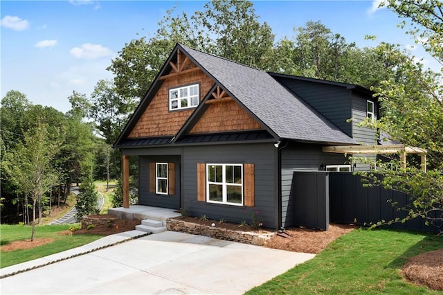 craftsman-style house with roof with shingles, a front yard, and fence