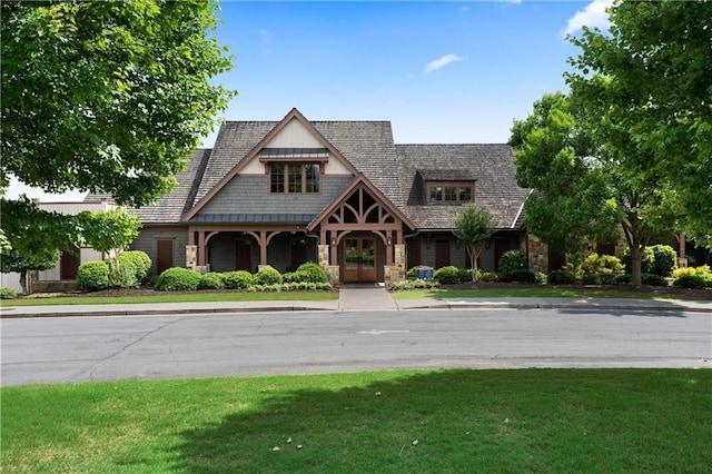 view of front facade featuring a front yard, french doors, and stone siding