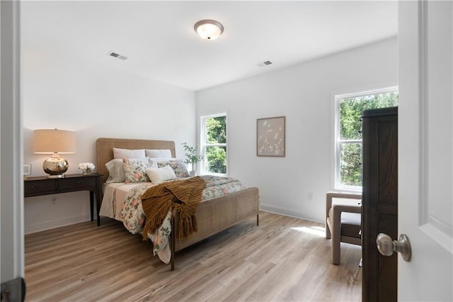 bedroom with visible vents, baseboards, and light wood finished floors