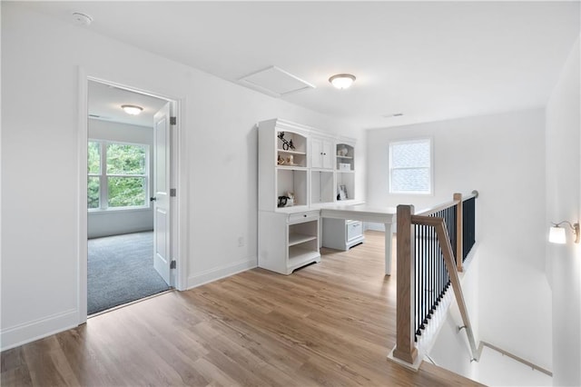 corridor featuring an upstairs landing, a healthy amount of sunlight, attic access, and light wood-type flooring