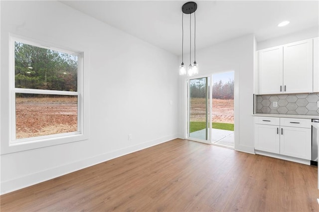 kitchen featuring a center island, light hardwood / wood-style flooring, hanging light fixtures, appliances with stainless steel finishes, and white cabinets