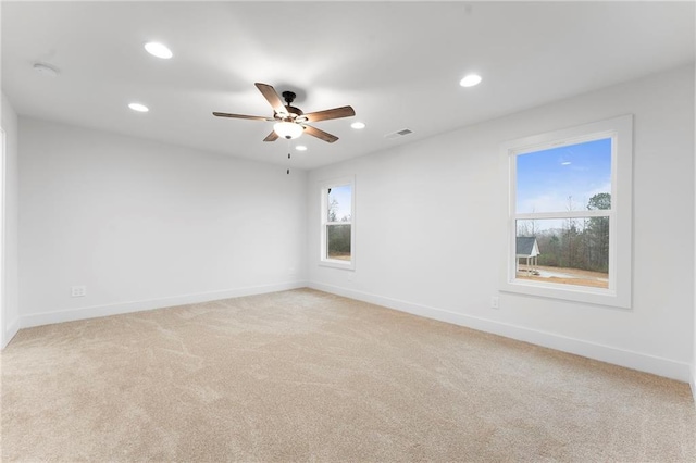 carpeted spare room featuring plenty of natural light and ceiling fan