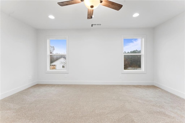 empty room with ceiling fan, a healthy amount of sunlight, and carpet