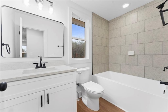 full bathroom featuring hardwood / wood-style flooring, vanity, toilet, and tiled shower / bath combo