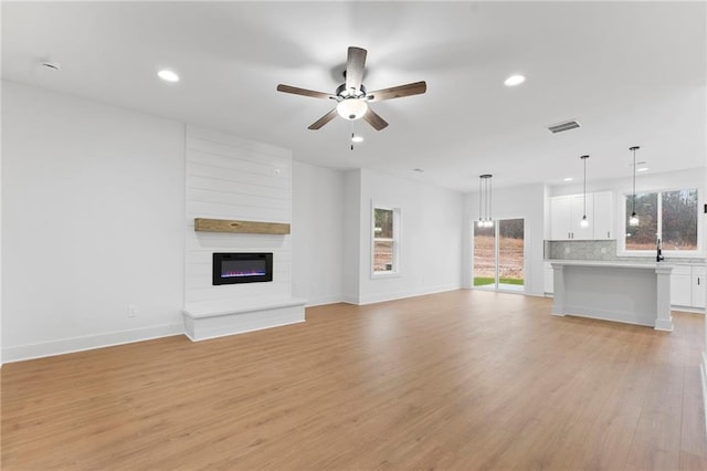 unfurnished living room featuring a large fireplace and light hardwood / wood-style flooring