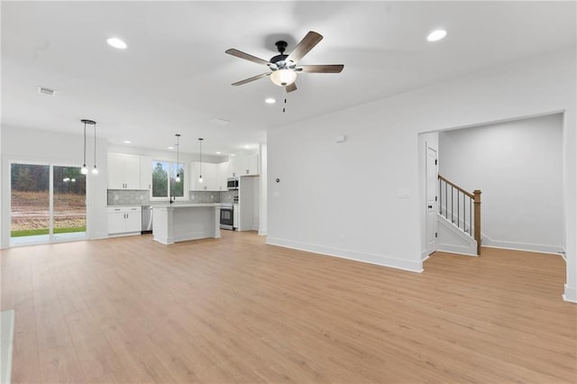 unfurnished living room with light hardwood / wood-style floors, a large fireplace, and ceiling fan