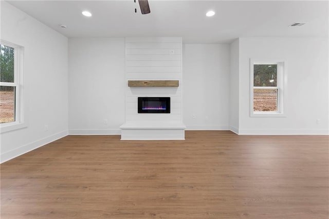 unfurnished living room with ceiling fan, a fireplace, and light hardwood / wood-style flooring