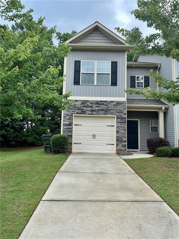 664 Oakside Pl, Acworth, GA 30102 - view of front facade with stone siding, a front lawn, an attached garage, driveway, and board and batten siding