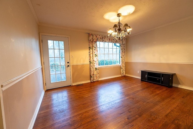 unfurnished dining area featuring an inviting chandelier, plenty of natural light, crown molding, and dark wood-type flooring