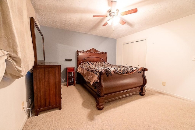 bedroom with a textured ceiling, light colored carpet, a closet, and ceiling fan