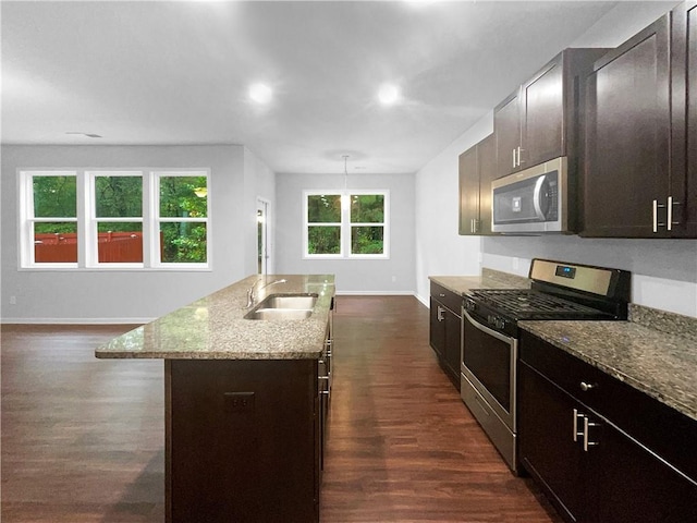 kitchen with a center island with sink, appliances with stainless steel finishes, sink, and dark hardwood / wood-style flooring