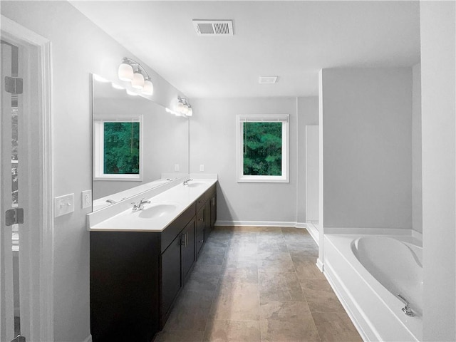 bathroom with a tub to relax in, vanity, and a wealth of natural light