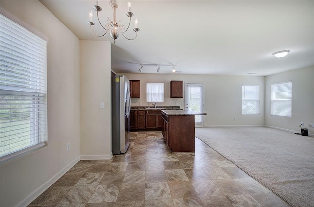 kitchen featuring baseboards, freestanding refrigerator, a sink, and a chandelier