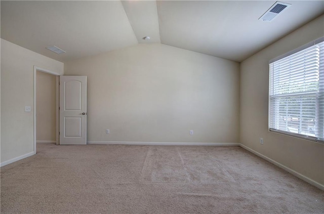 carpeted empty room featuring baseboards, lofted ceiling, and visible vents