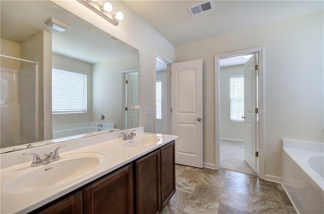 full bath with visible vents, a sink, baseboards, and a garden tub