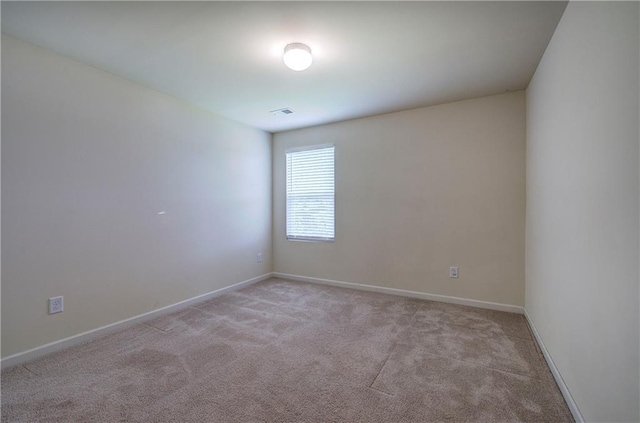 empty room featuring baseboards and light colored carpet