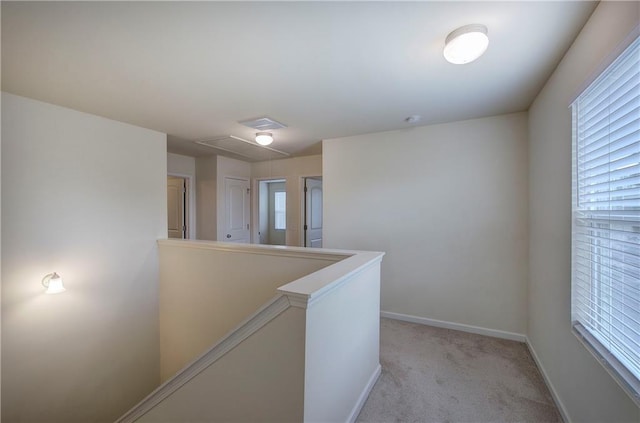 corridor with light colored carpet, baseboards, a wealth of natural light, and an upstairs landing