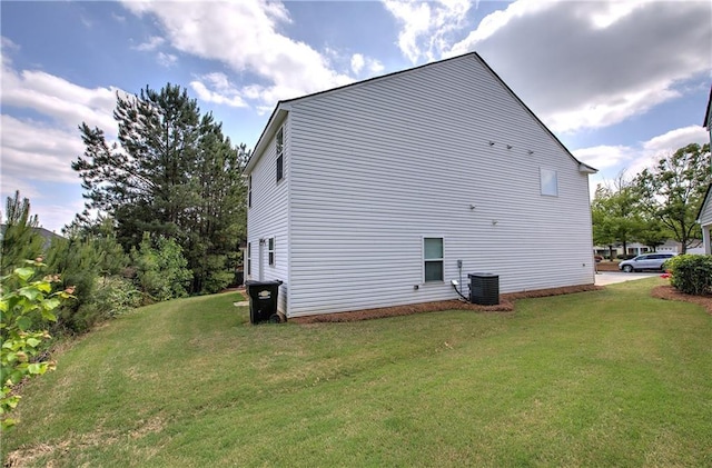 view of side of home with central AC unit and a yard