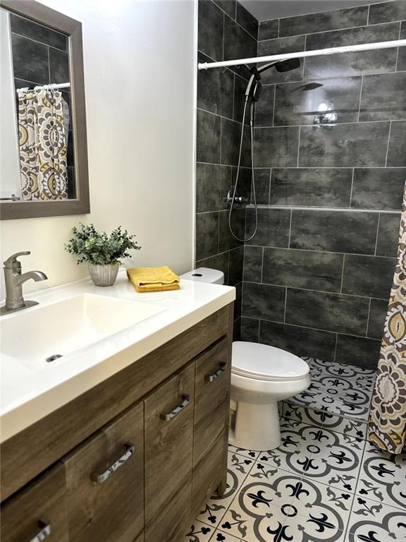 bathroom featuring tile patterned flooring, a shower with curtain, toilet, and vanity