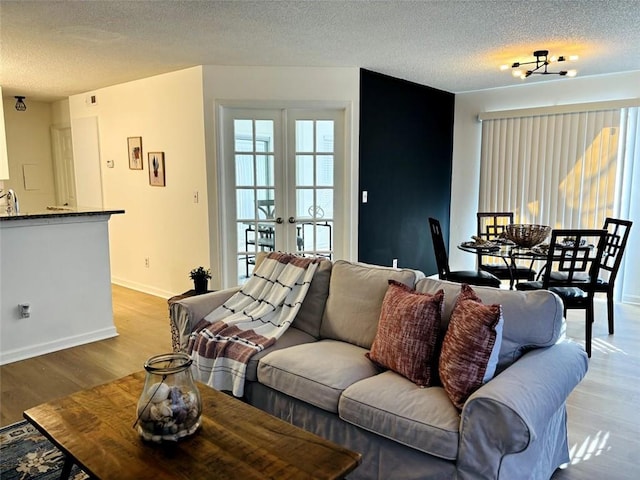 living room with light wood-type flooring, a textured ceiling, and french doors