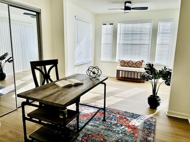 dining area with ceiling fan, wood-type flooring, and a textured ceiling