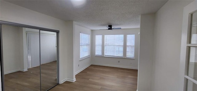 unfurnished bedroom with ceiling fan, light wood-type flooring, a textured ceiling, and a closet