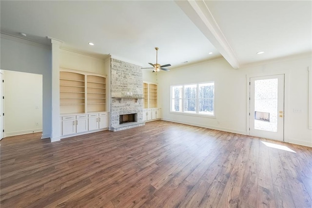 unfurnished living room with built in features, ornamental molding, beamed ceiling, and a fireplace