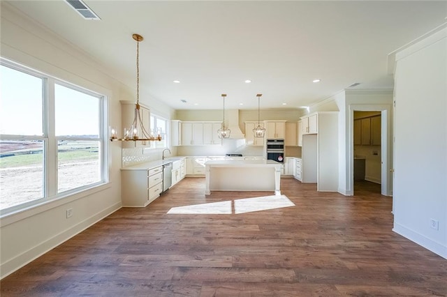 kitchen with hanging light fixtures, white cabinets, appliances with stainless steel finishes, and a kitchen island